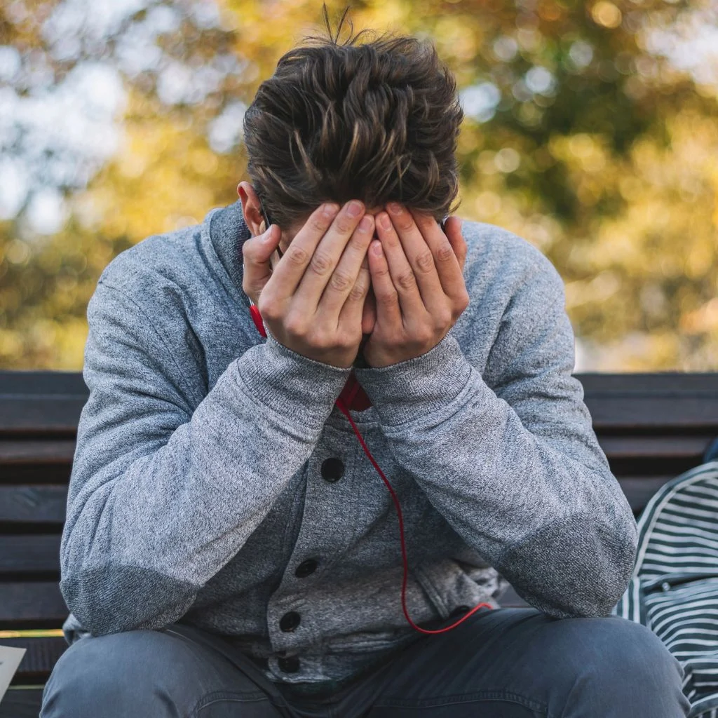 a man sitting down hands over face in crisis