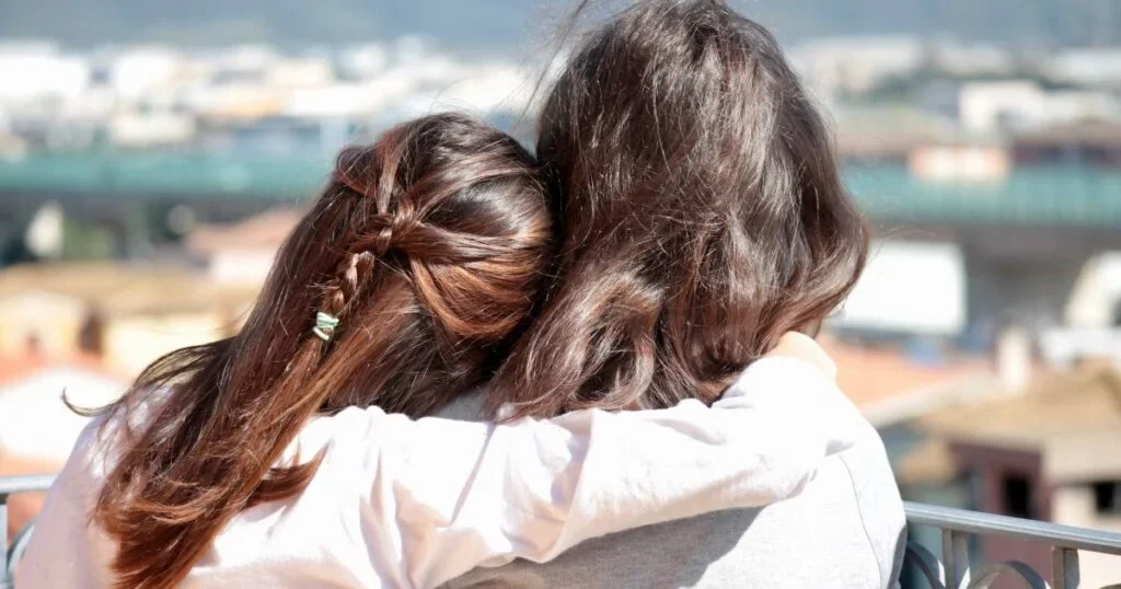 Two young sisters embracing.